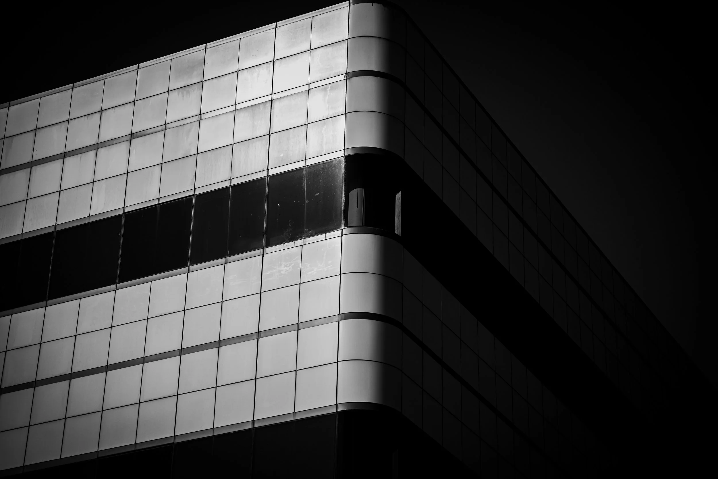 Light catches the rounded corner and gridded facade of a modern building.