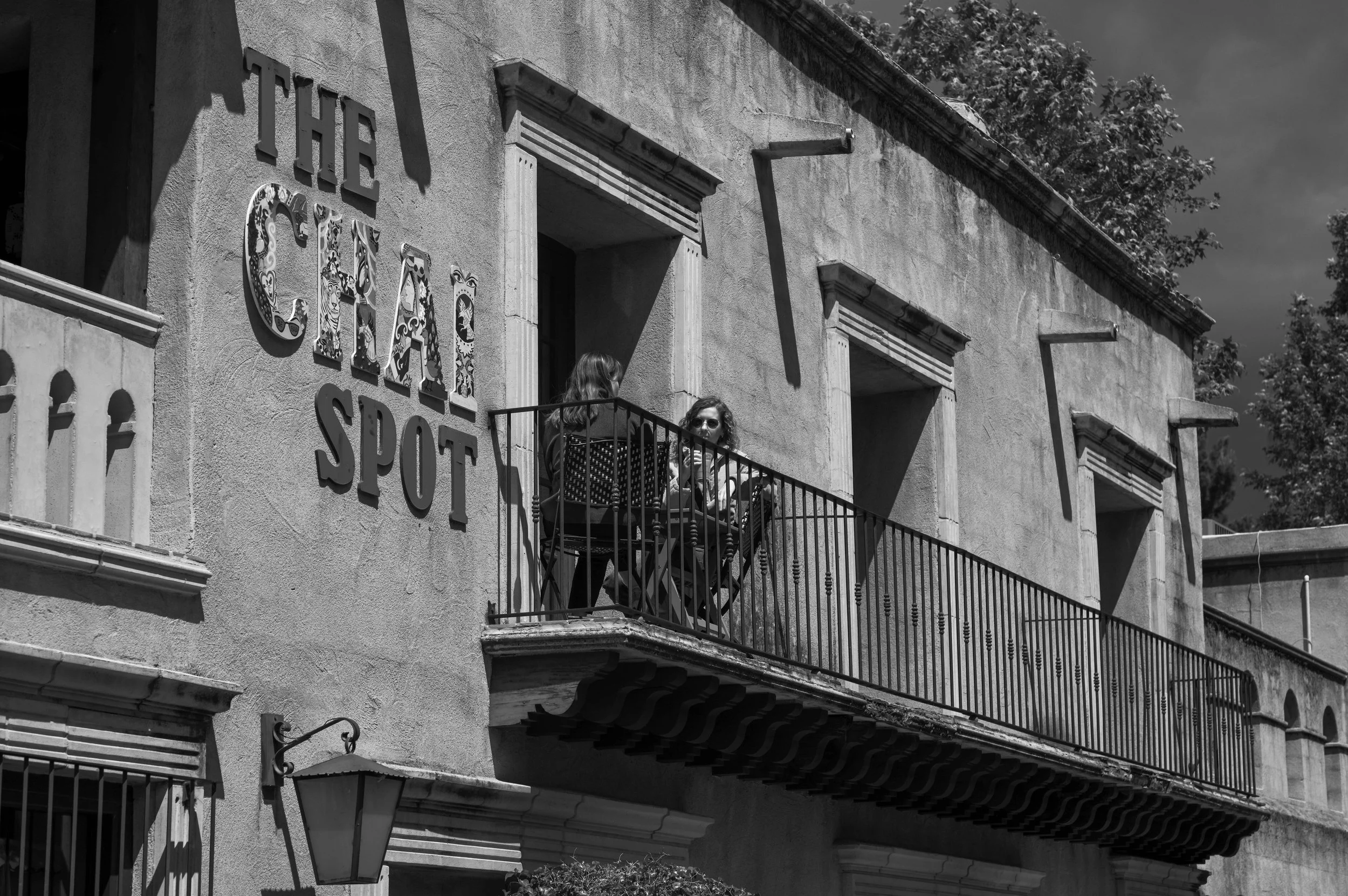 People gather on a balcony above a street.