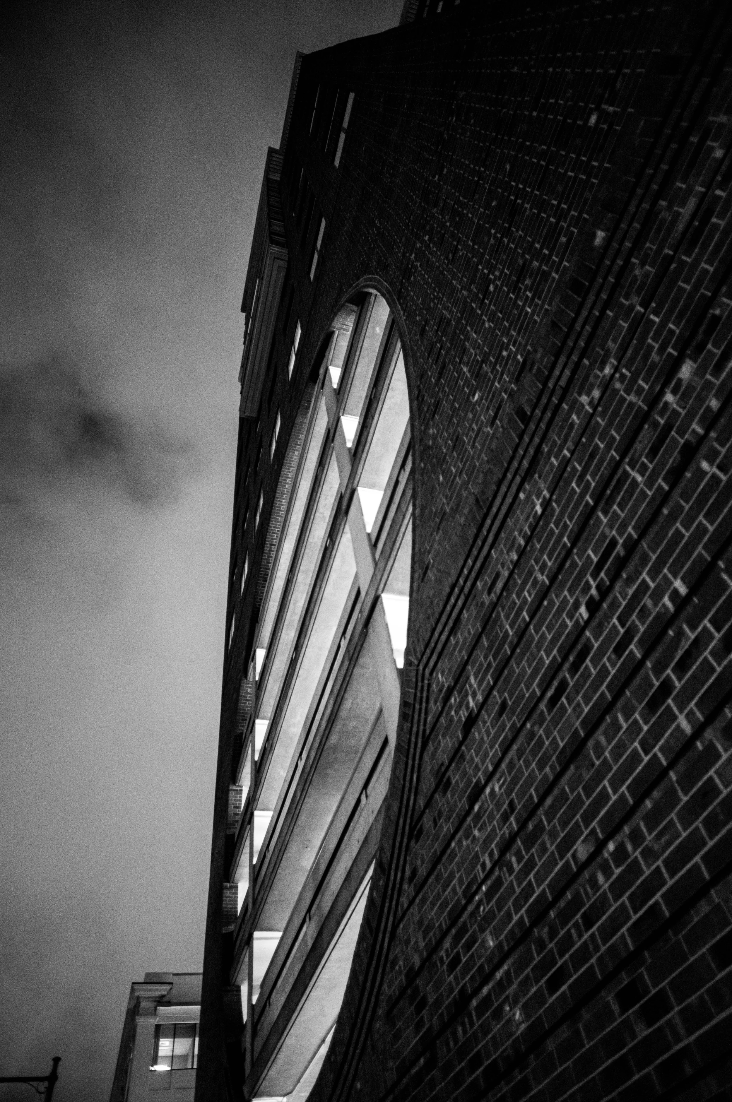 Light from a window grazes a brick wall in a steep nighttime perspective.