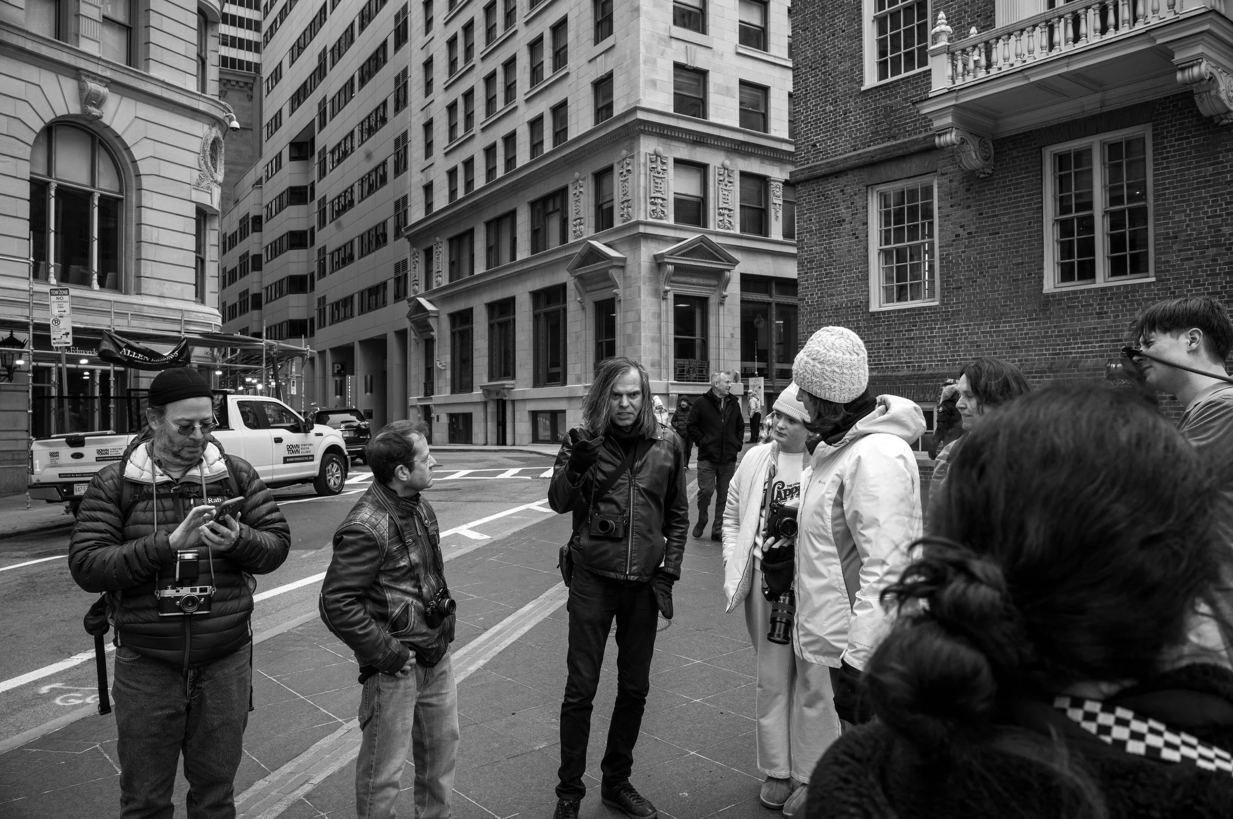 A group of people gathers on a city sidewalk.