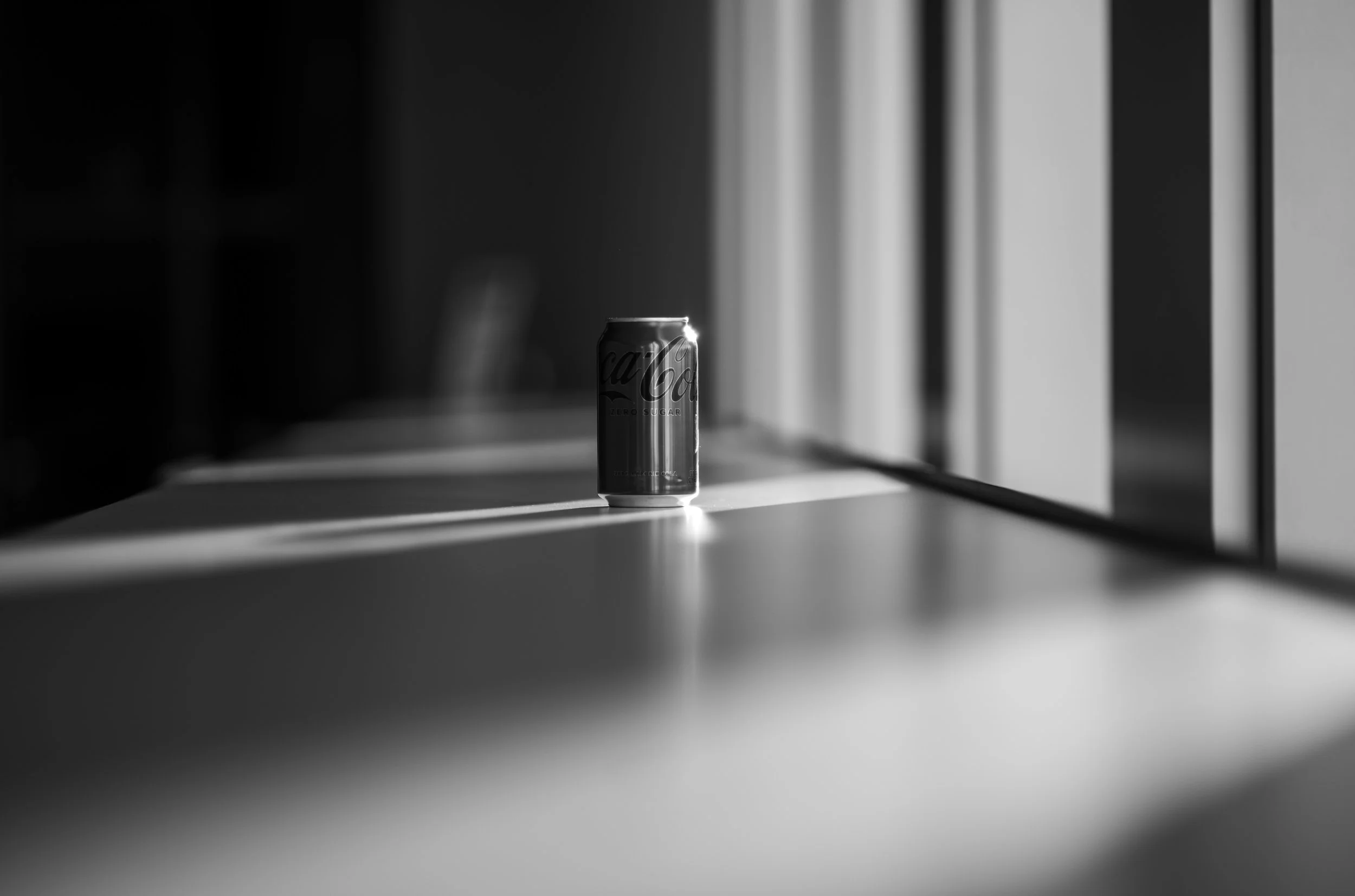 A small metal cylinder catches a narrow beam of window light on a tabletop.