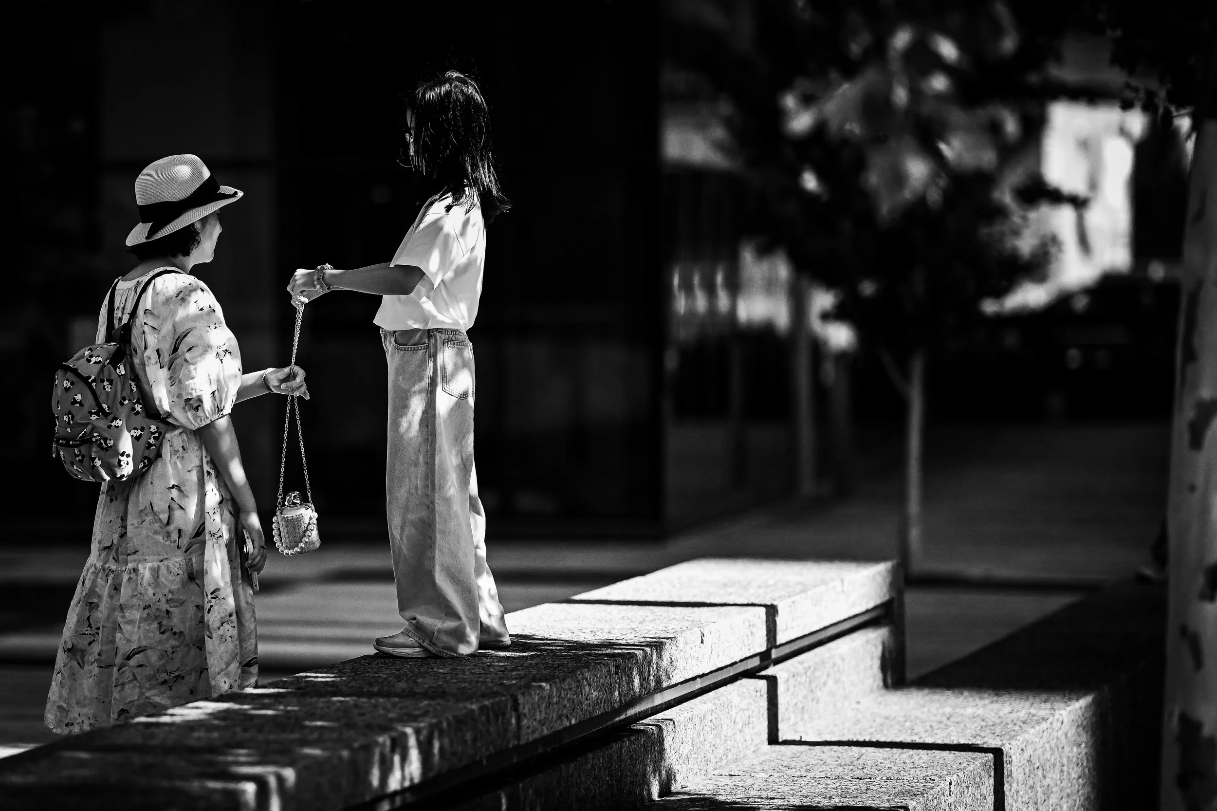 Two people stand in sunlight on broad city steps.