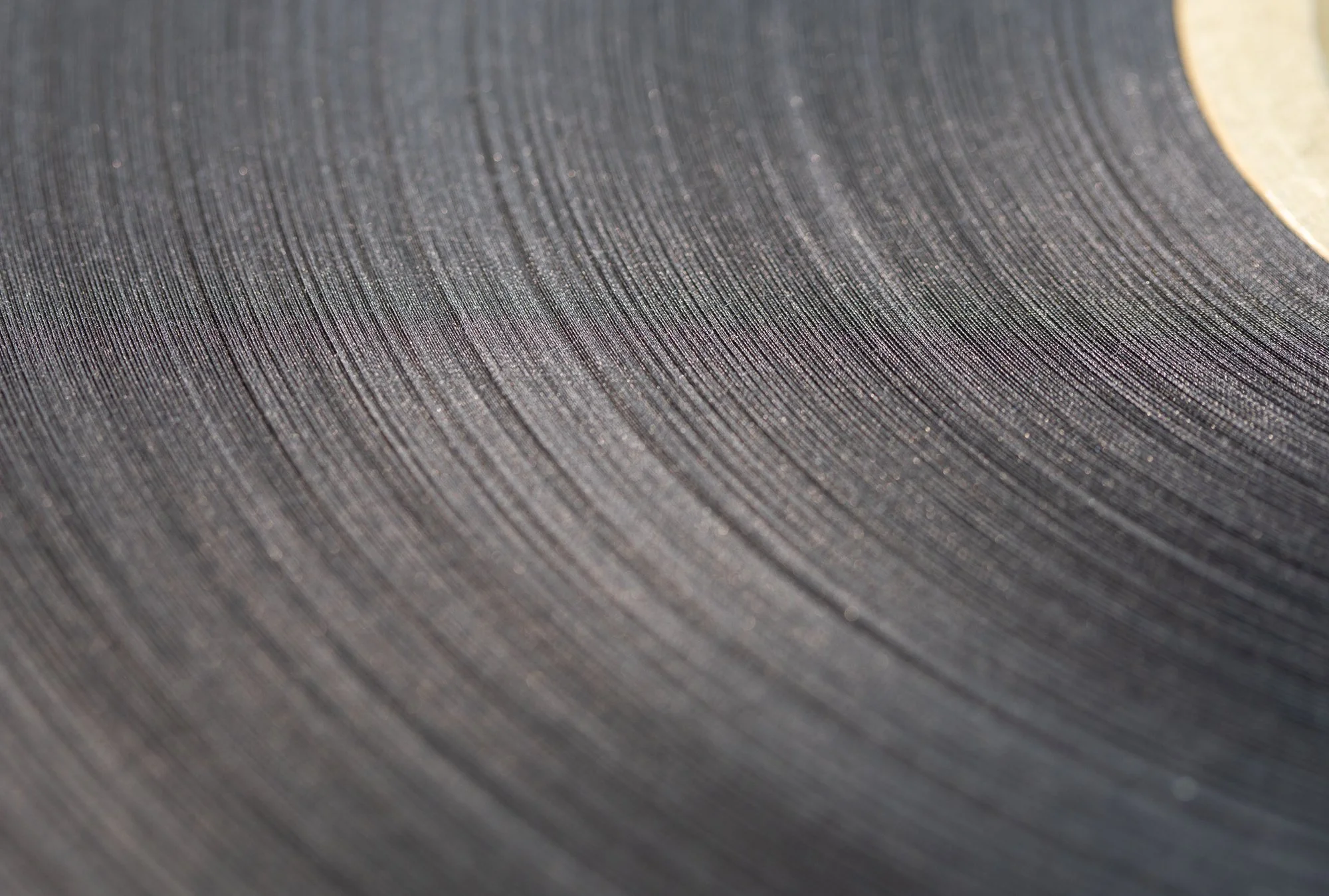 Close-up of a vinyl record with visible grooves and a partially visible label on the right edge.