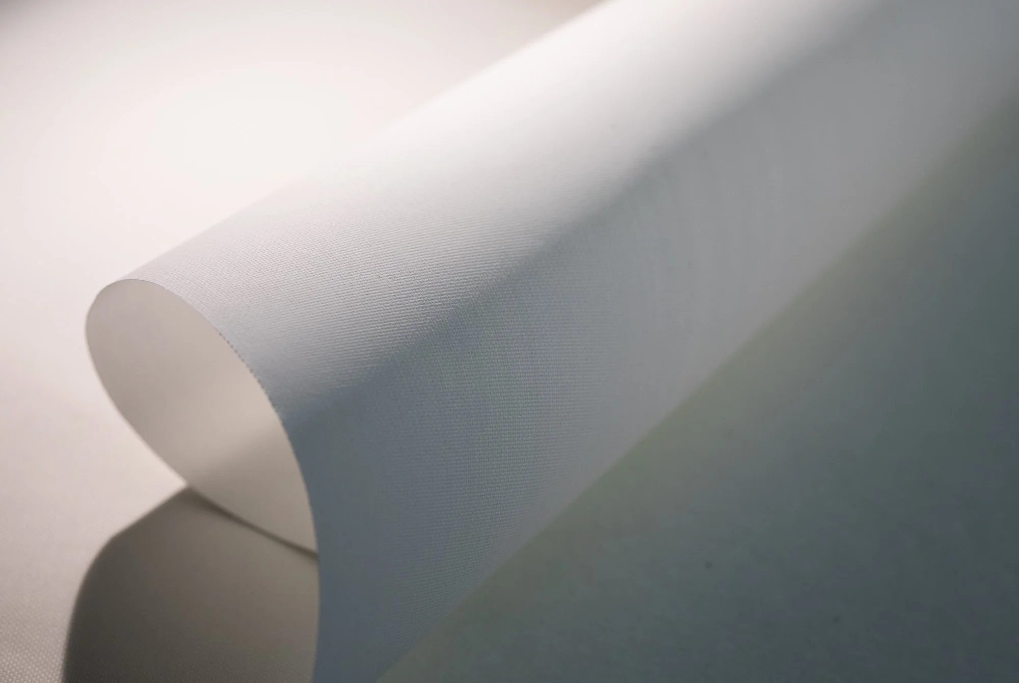 Close-up of a white, textured, cylindrical object, possibly paper or fabric, with soft shadows.