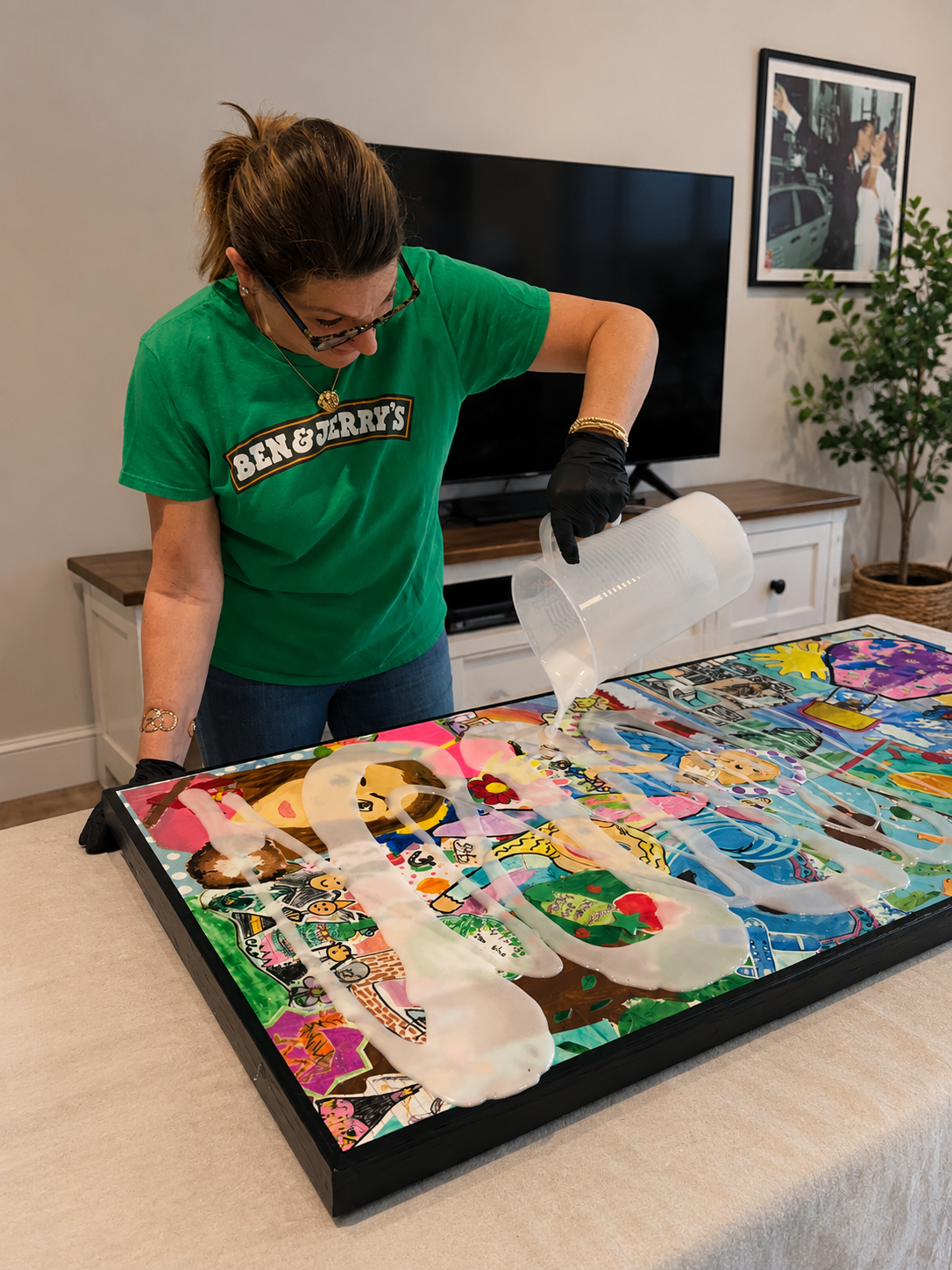 Woman pouring white liquid over colorful graffiti-style artwork on a table.