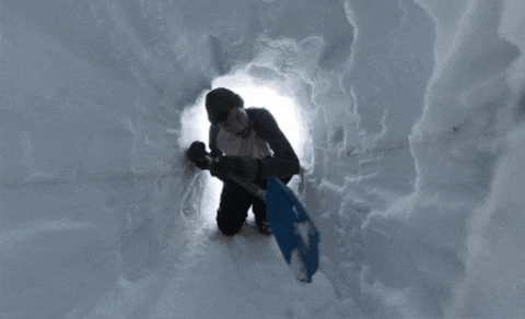 A person inside a snow cave or tunnel digging