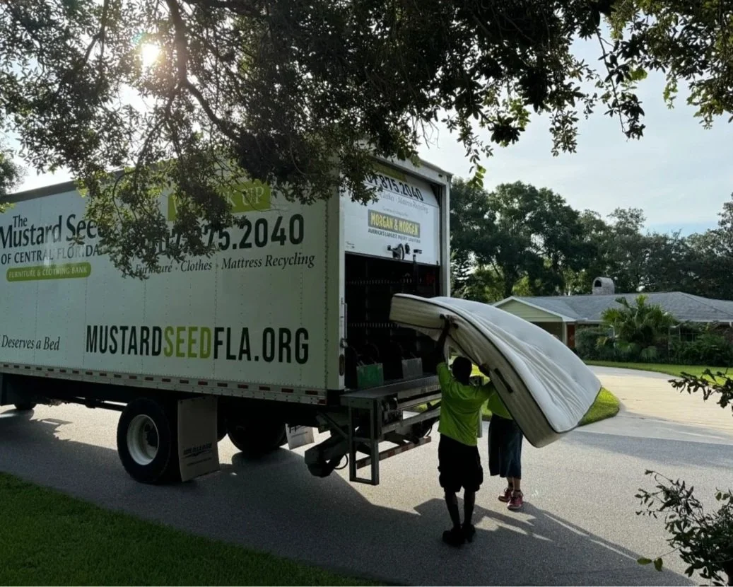 Volunteers loading a mattress into a truck on a suburban street.