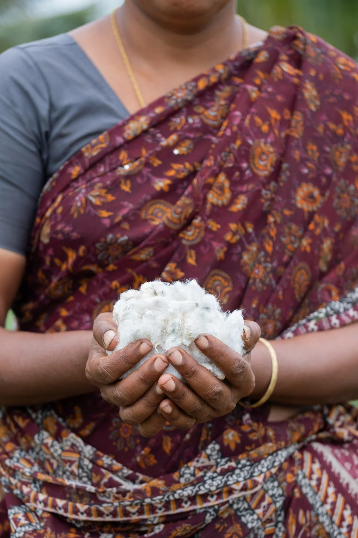 A person holding a large bundle of raw cotton with both hands.