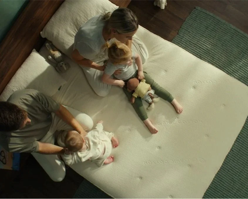 Birds-eye view of family sitting on a mattress.