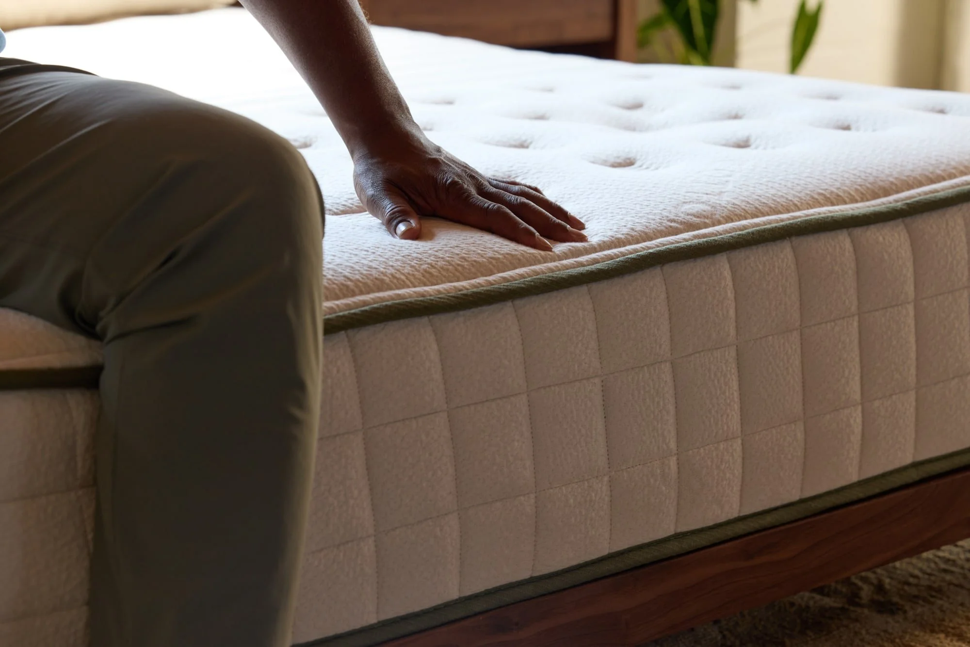 Close-up of a person pressing their hand on a padded mattress.