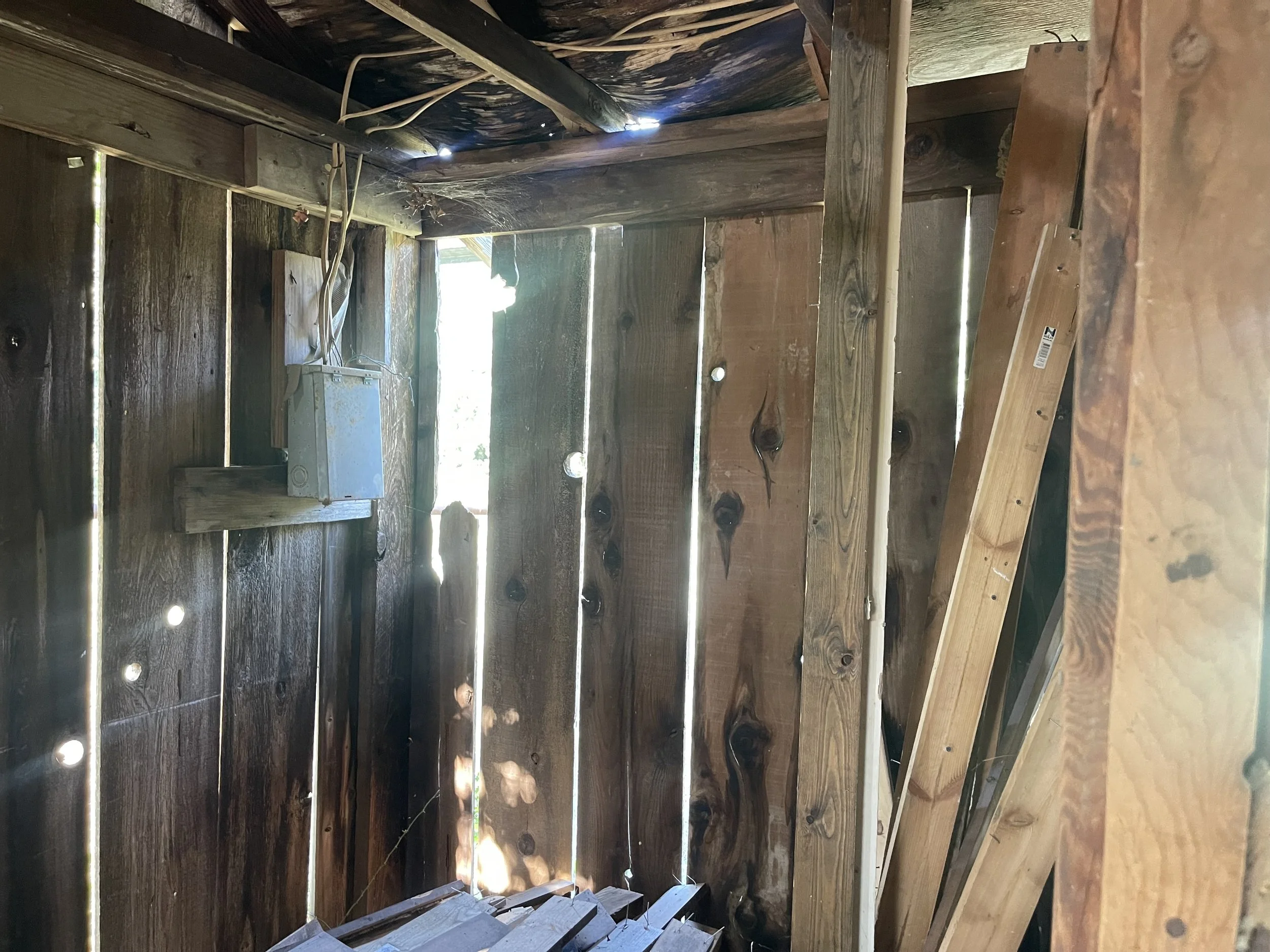 Part of a wooden structure with sunlight coming through gaps in the wood.