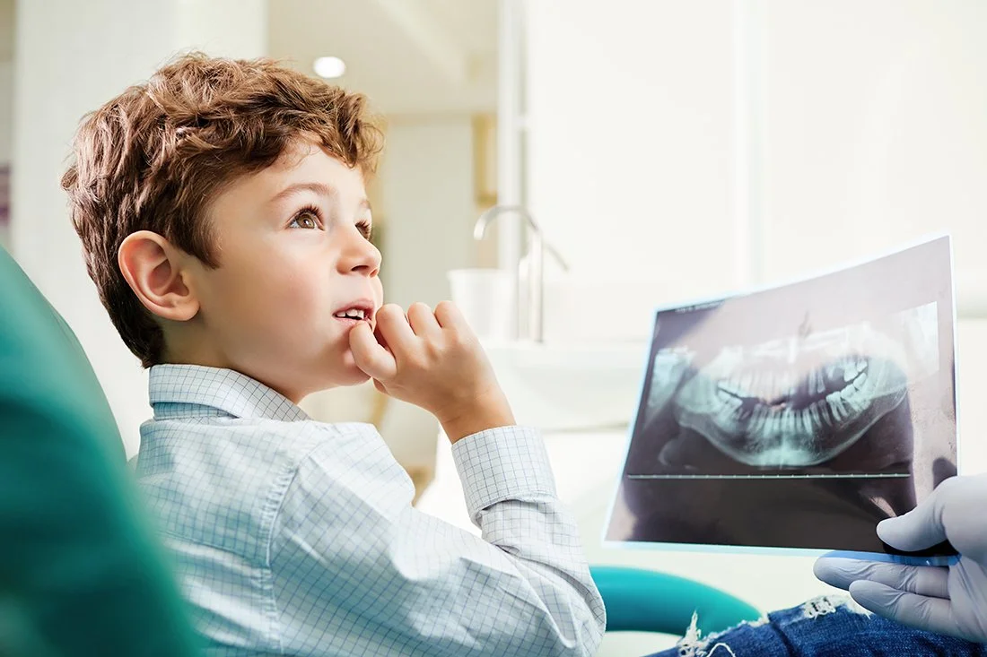 Child in a dental office looking at a dental X-ray.