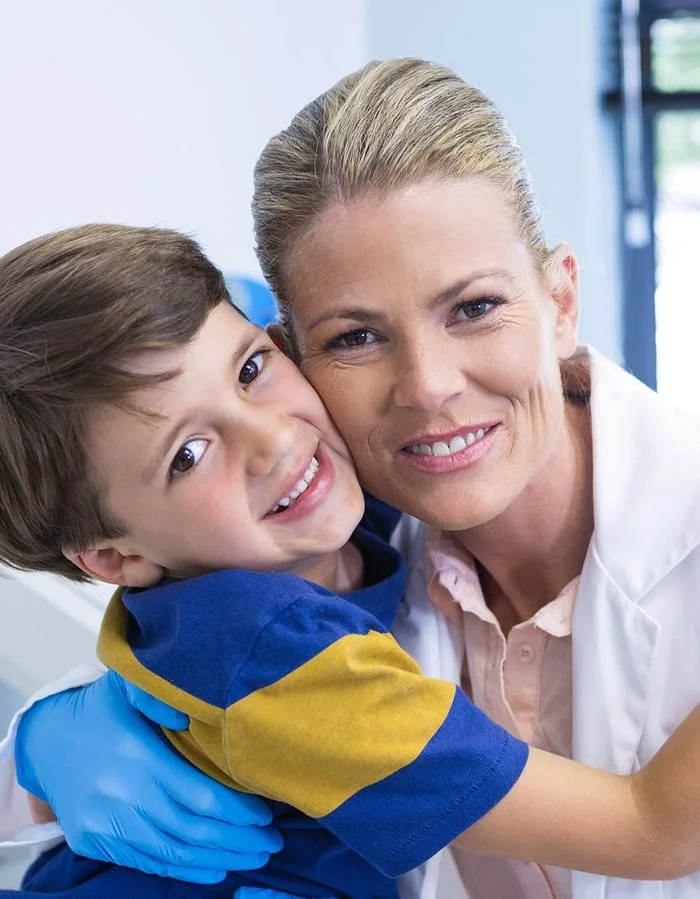 A young boy hugging a smiling female dentist.