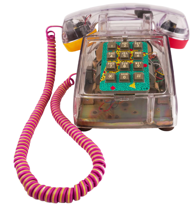 A vintage transparent rotary corded telephone with a colorful, geometric patterned keypad cover. The phone has a pink and yellow striped coiled cord and a clock face on top of the handset.
