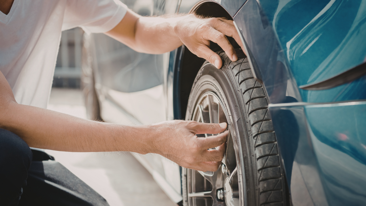 A person changing or inspecting a car tire.