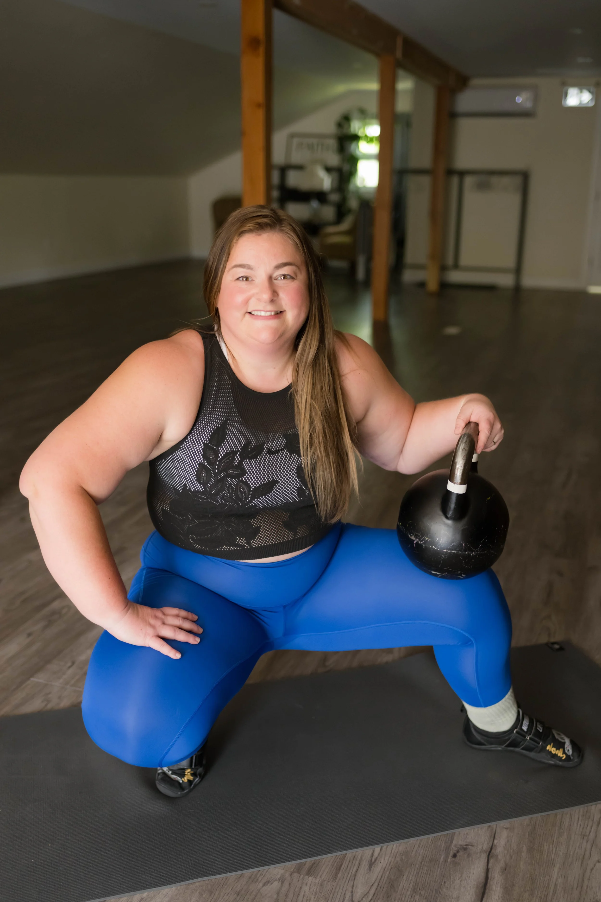 Laura Smiling at camera holding a kettlebell. Located at The Hive Fitness and Yoga Studio