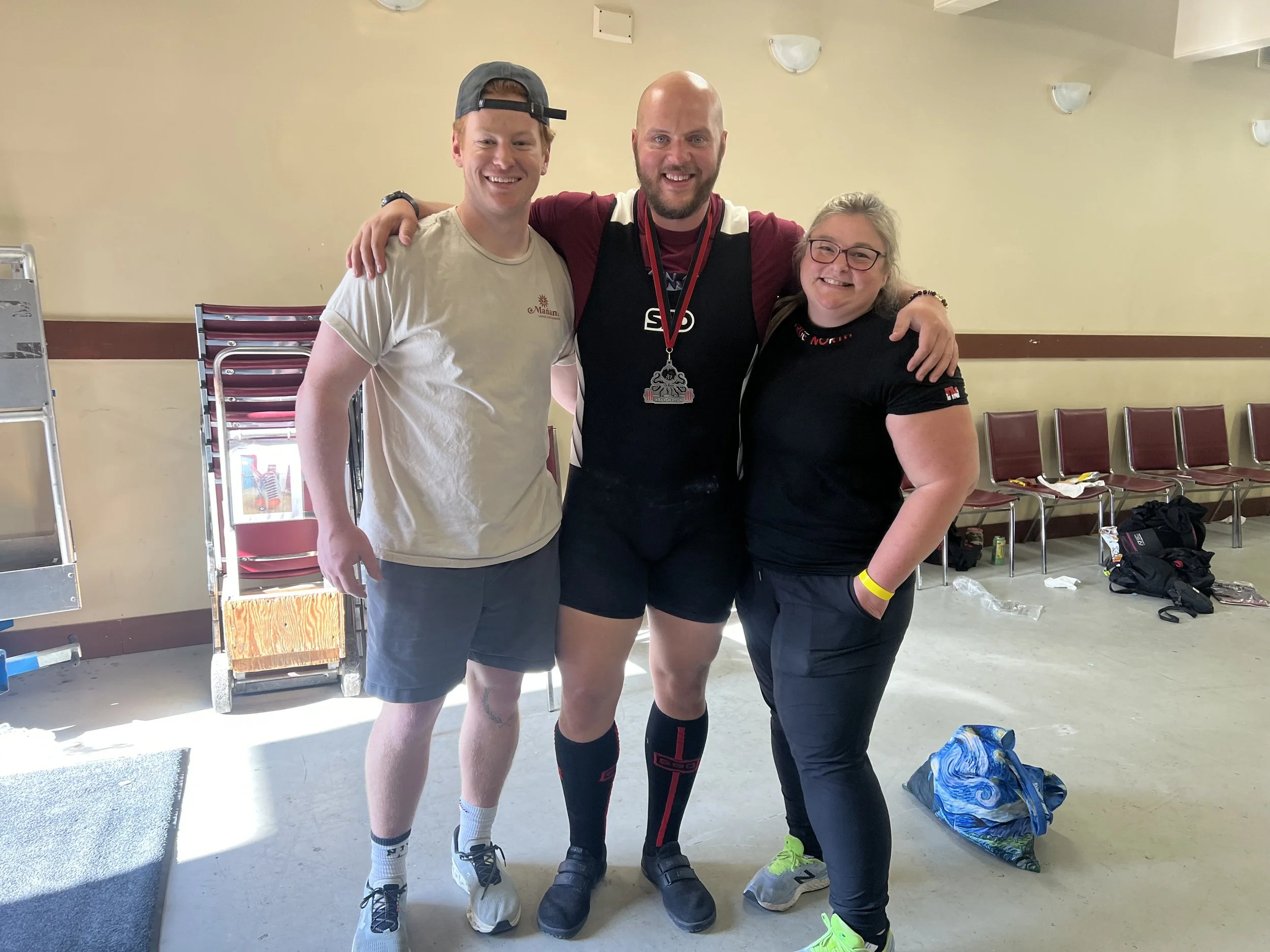 Laura at the Kraken Open Powerlifting Meeting posing  with 2 other male powerlifting athletes