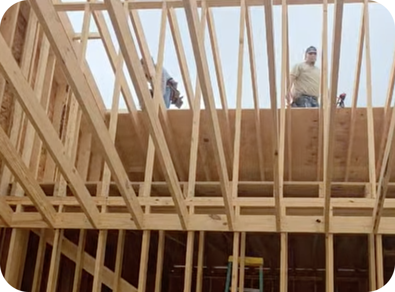 Two construction workers standing on the wooden frame of a building under construction.