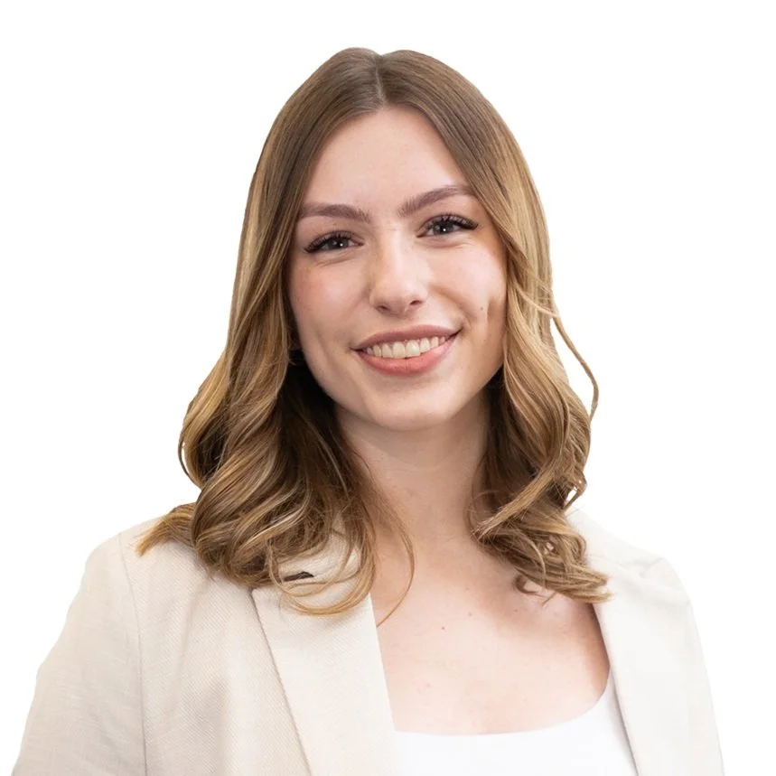 A young woman with shoulder-length wavy hair, smiling, wearing a light-colored blazer over a white top, against a plain white background.