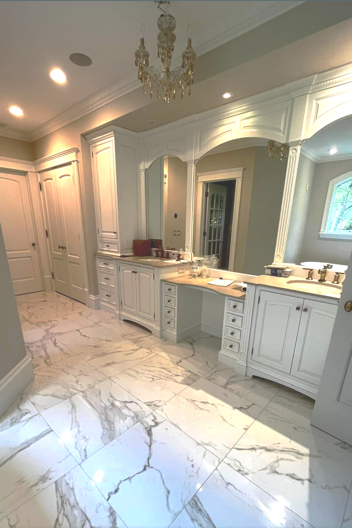 Bathroom with white cabinetry, marble floors, and a chandelier.