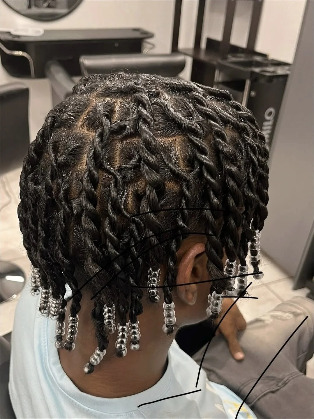 Close-up of a person's head showcasing freshly styled box braids adorned with silver beads.