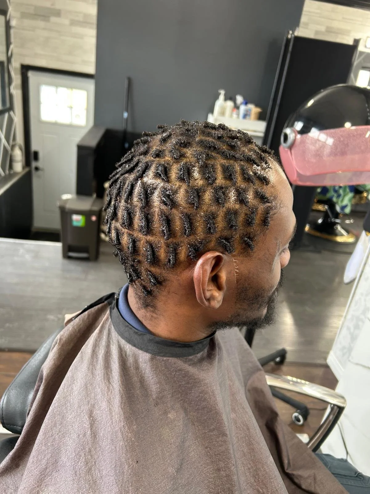 Man getting his hair styled with twists in a salon.