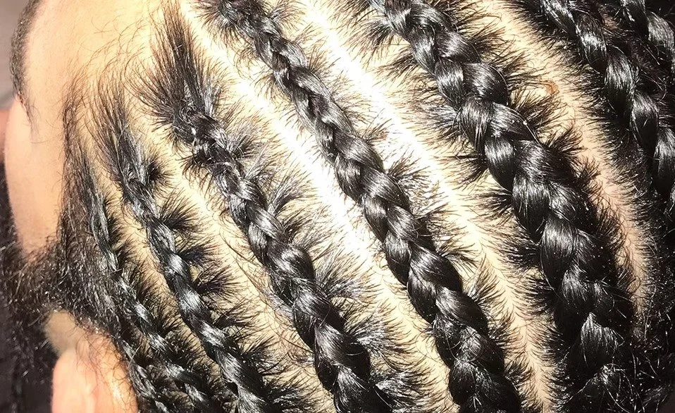 Close-up of a person's scalp with neatly braided hair.