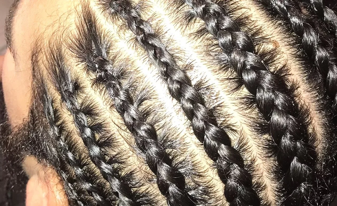 Close-up of a person's scalp with neatly braided black hair.
