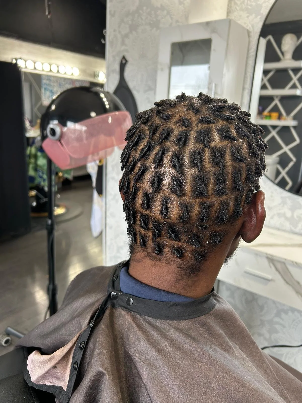 Back of a person's head with freshly styled dreadlocks, featuring a pattern shaved into the hair.