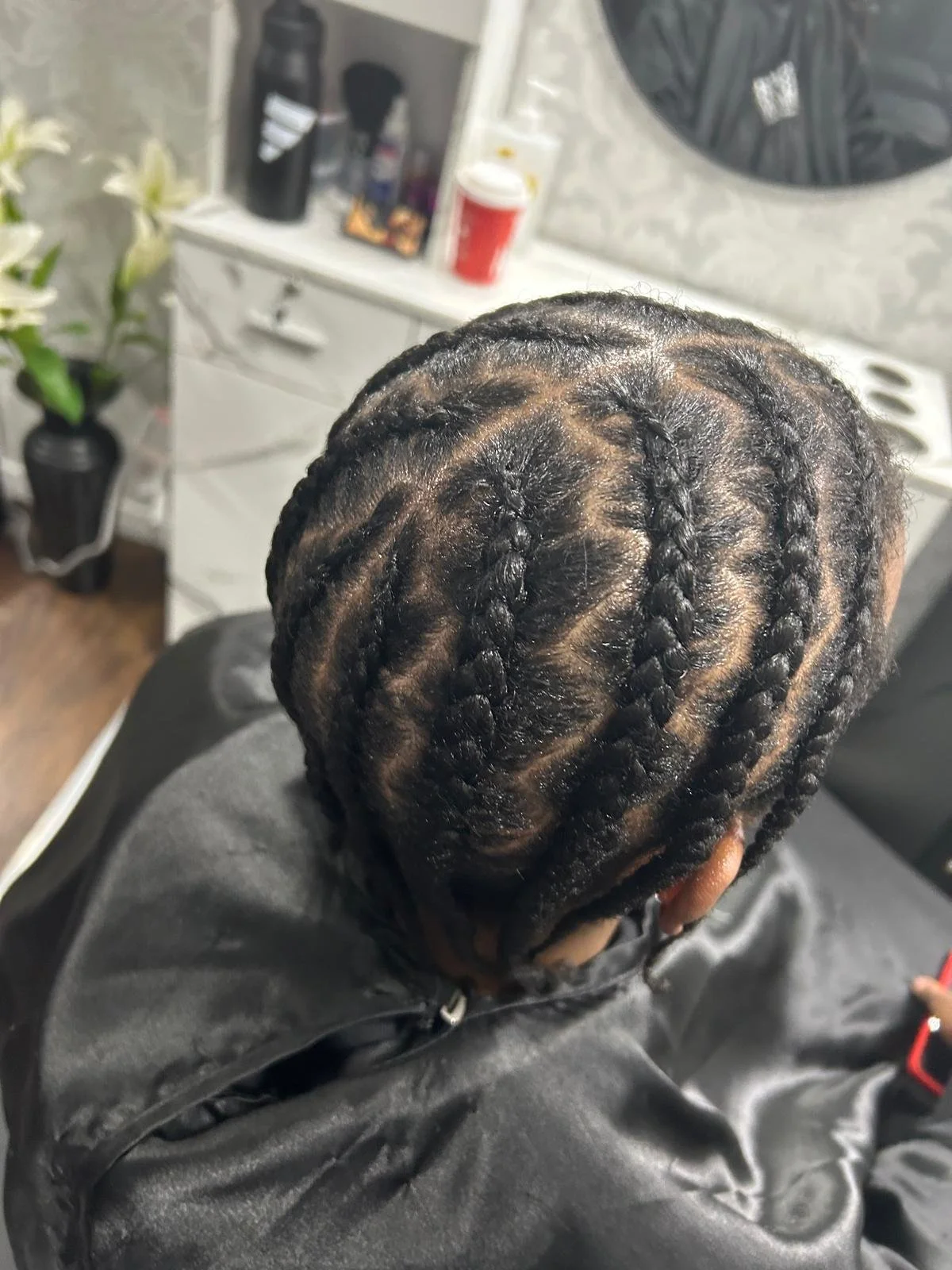 Person with freshly braided hair sitting in a chair in a salon.