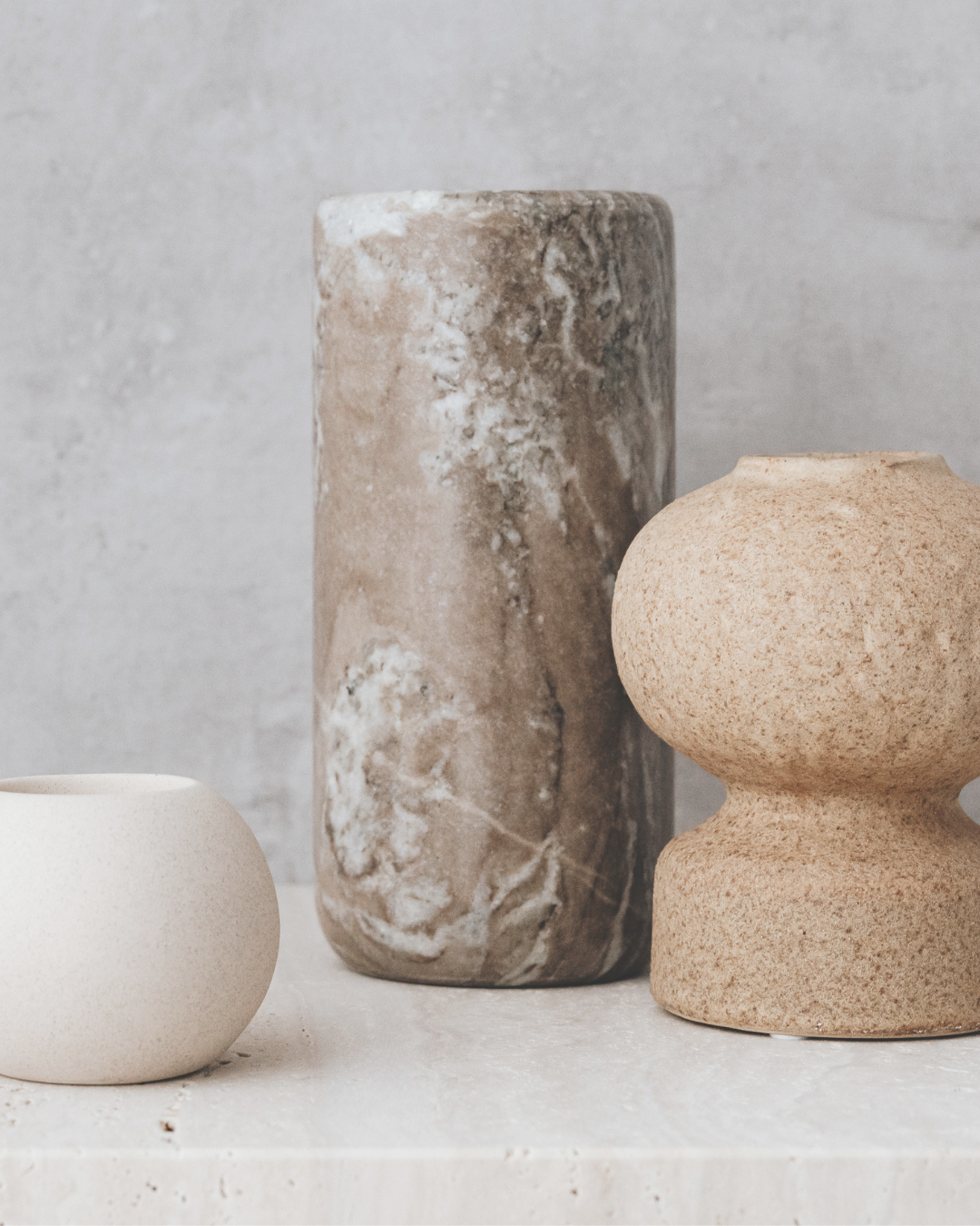 Three modern decorative vases in neutral tones, with different shapes and textures, displayed against a minimalist background.