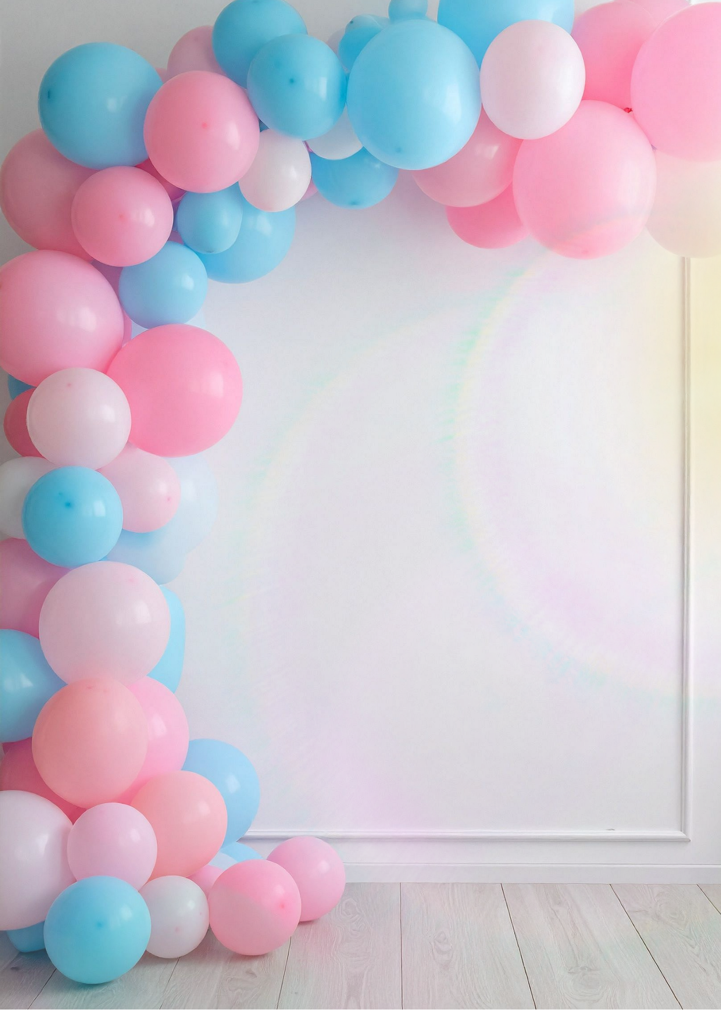 Pink, blue, and white balloons arranged as a cascading arch against a white wall.