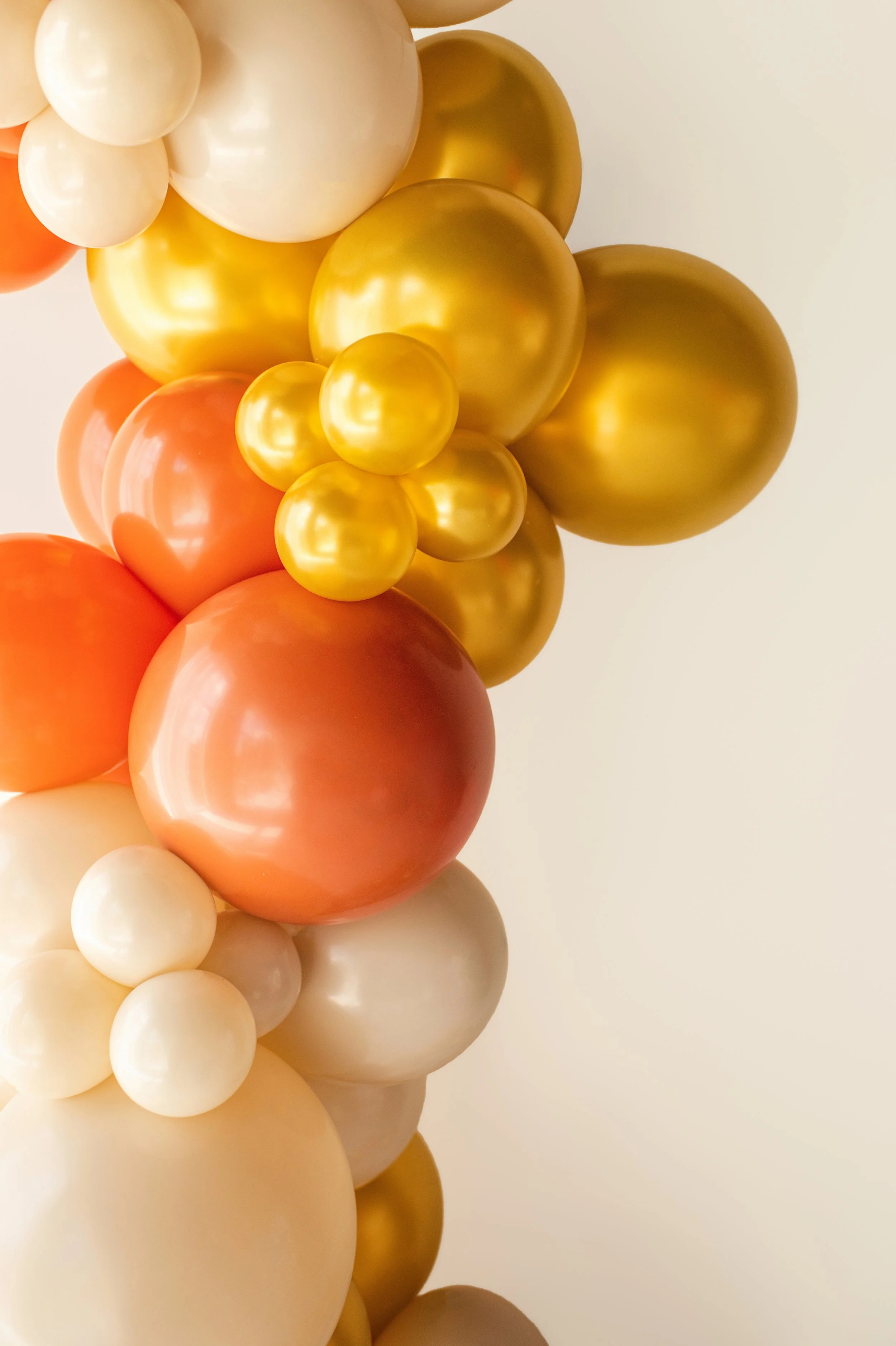 A close-up view of a cluster of balloons in white, gold, and peach colors.