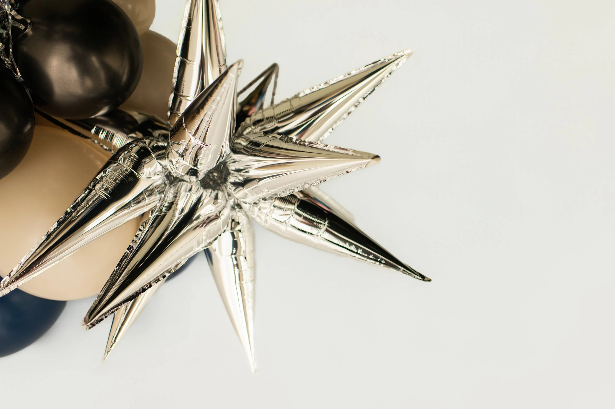 Silver star-shaped hollow object on a white background, with black and white spherical decorations nearby.