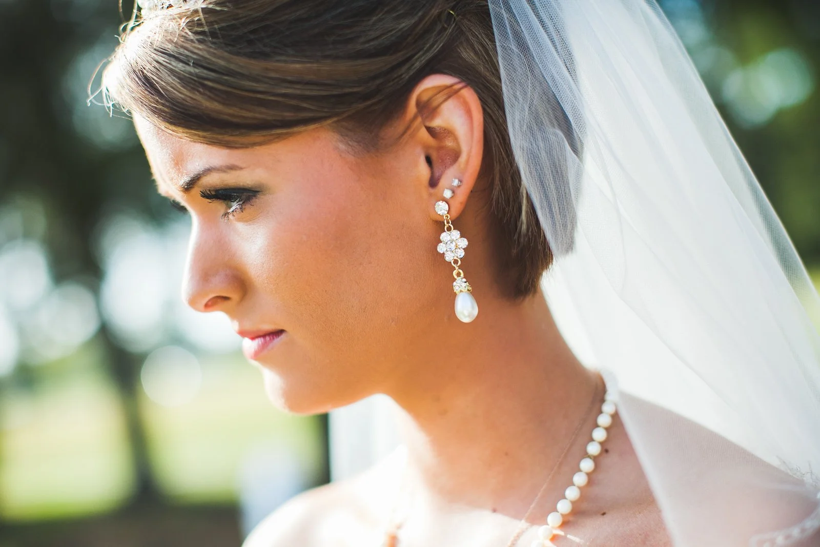 Bride in profile wearing pearl drop earrings and veil