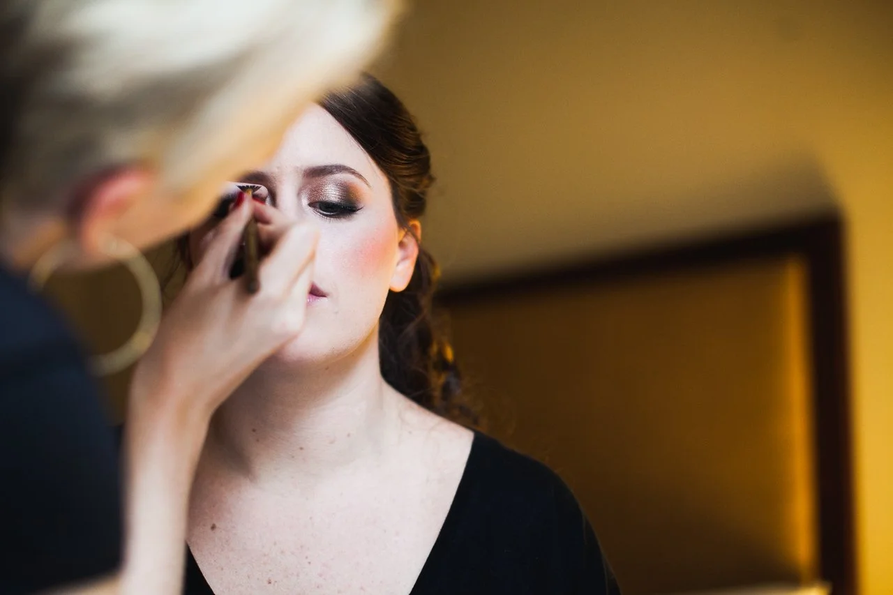 Makeup artist applying eyeshadow to a woman in a black top