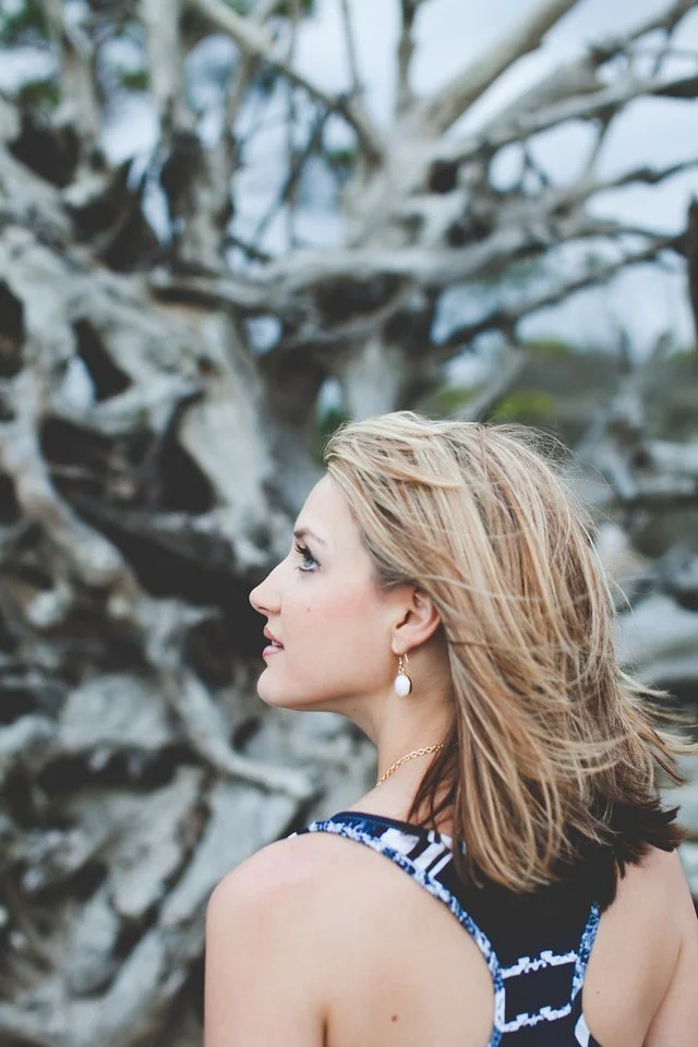 Woman in profile with blonde hair against bare winter trees