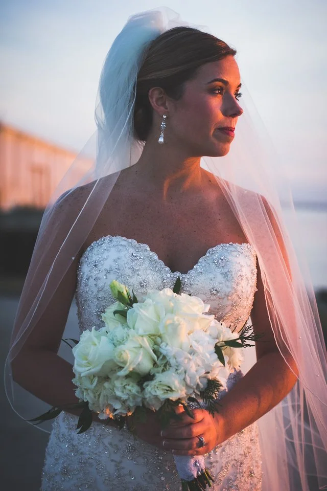 Bride in a beaded strapless gown holding a white bouquet