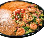 Shrimp and vegetable stir-fry with sesame seeds on a black plate