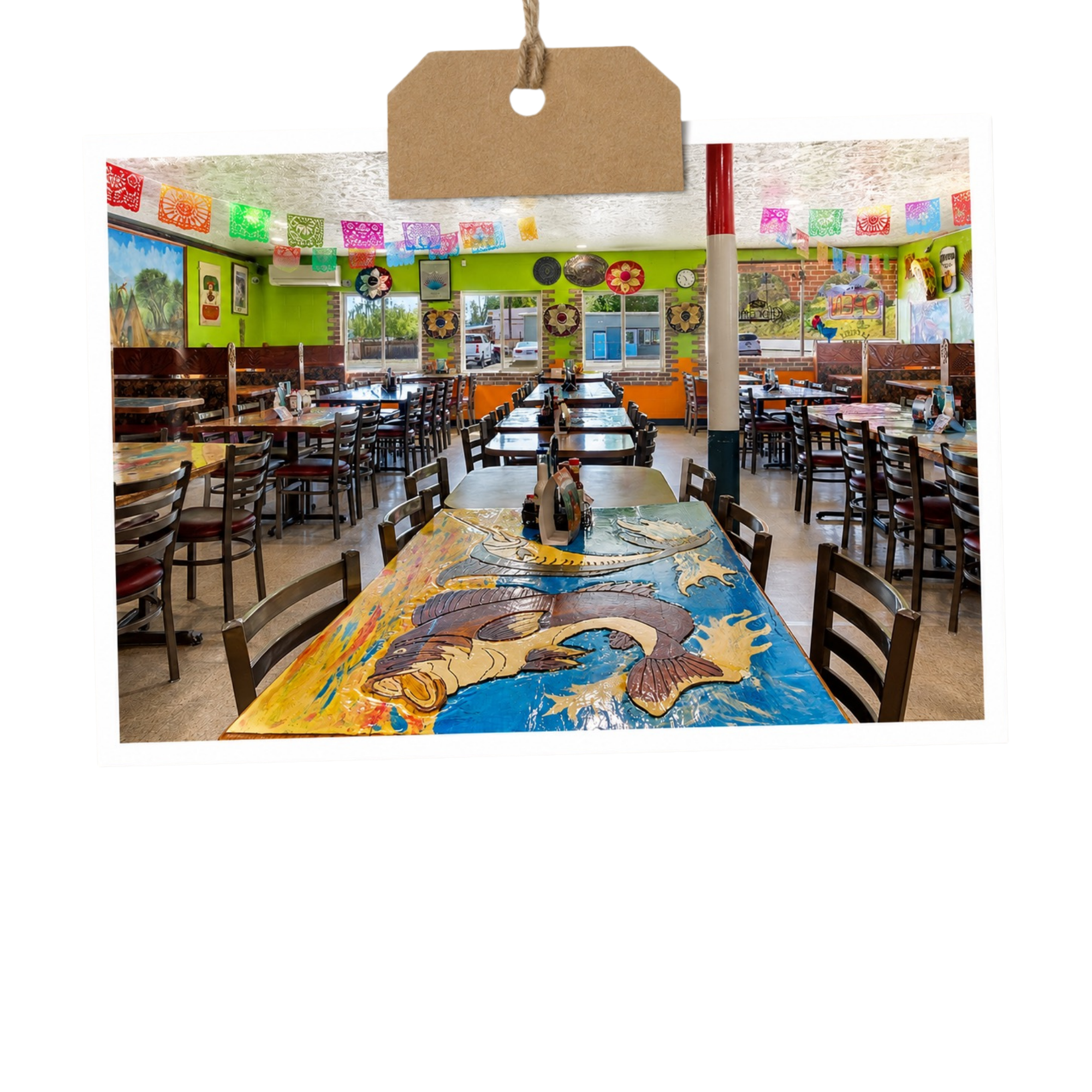 Colorful interior of a restaurant with green walls, decorated with various artwork and papel picado banners, wooden tables, and chairs.