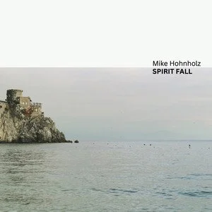 A coastal cliff with buildings overlooking the water, and a cloudy sky. Text on the image reads 'Mike Hohnholz SPIRIT FALL'.