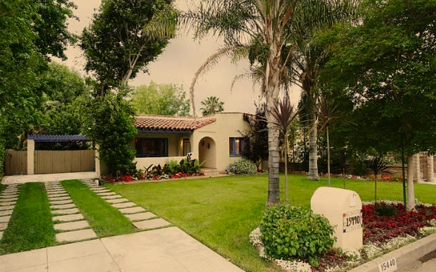 Front yard of a house with a well-kept lawn, concrete pathway, trees, and a mailbox.