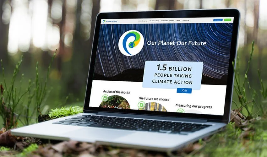 Laptop on forest floor displaying an environmental website titled "Our Planet Our Future" with a graphic of the Earth and stars, highlighting 1.5 billion people taking climate action.