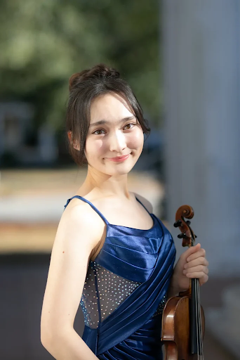 Young woman smiling outdoors holding a violin
