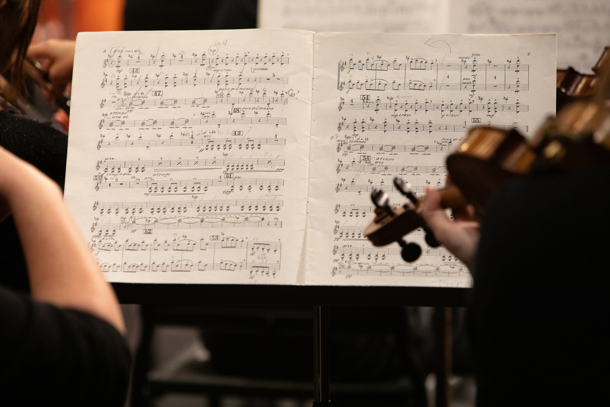 Sheet music and a violin being played during a performance.
