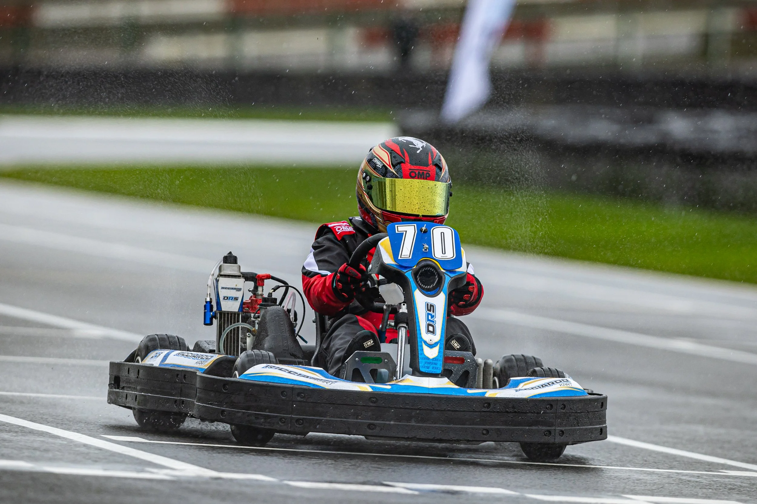 A person in a racing helmet driving a go-kart on a track.