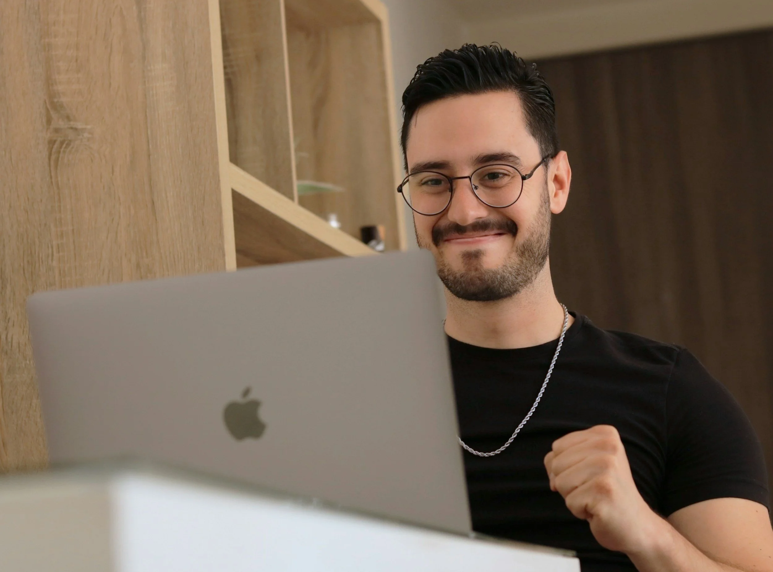 A man with glasses and a beard smiling while looking at a computer screen doing therapy