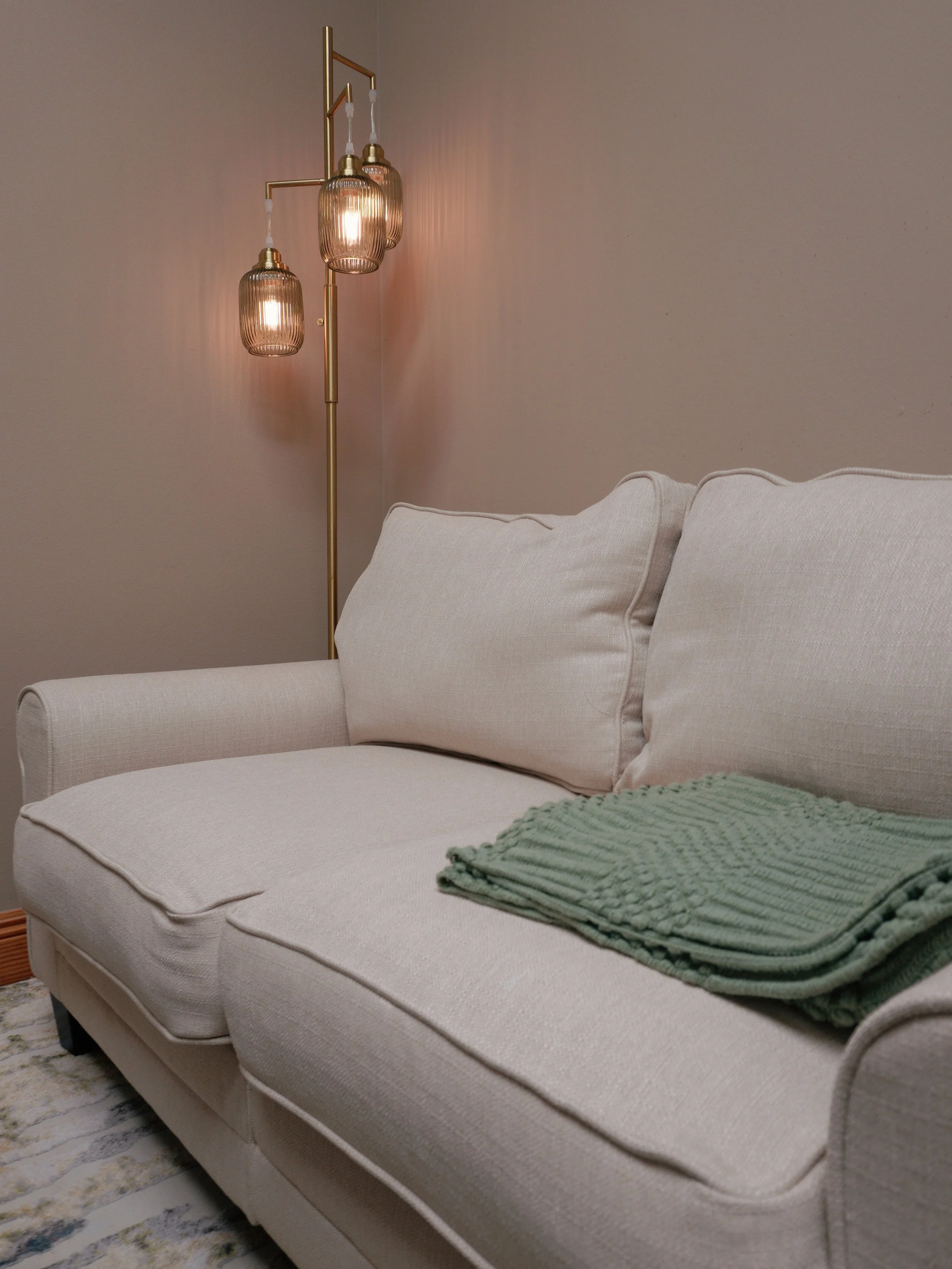 Comfortable therapy sofa with a green throw and warm lighting