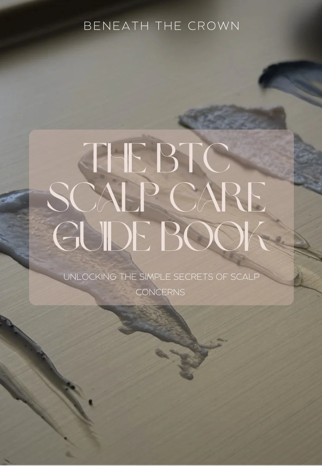 A book cover with the title 'Beneath the Crown The BTC Scalp Care Guide Book' over an image of several pieces of scalp treatment in a liquid form on a wooden surface. Trichology classes.