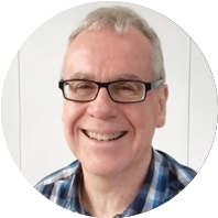 A smiling middle-aged man with glasses, short gray hair, and a checkered shirt.